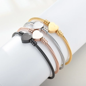 Detail of four-color woven cable wire heart bracelets in gold, silver, rose gold and black