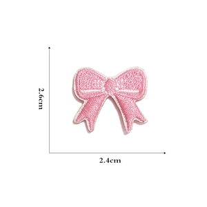 Detail view of pink bow embroidered patch with dimensions 2.4cm by 2.6cm on white background