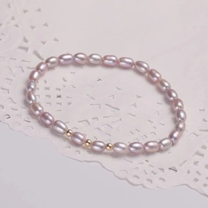 Elegante bracciale di perle d'acqua dolce lavanda con perline dorate su sfondo pizzo
