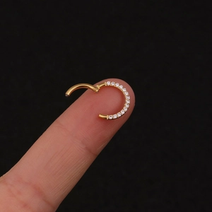 Polished gold stainless steel nose ring with zircon stones held by fingers