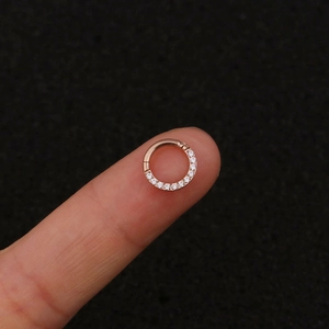 Macro shot of a rose gold stainless steel hoop ring with cubic zirconia on a fingertip