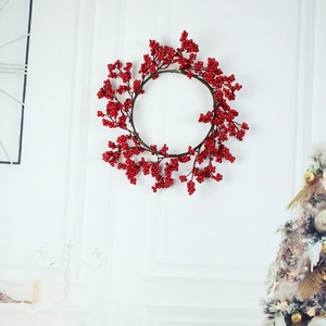 Artificial red berry Christmas wreath hanging on a white wall for festive home decor