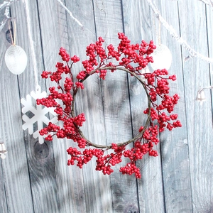 Close-up of a festive Christmas red berry wreath on a grey wooden surface with snow