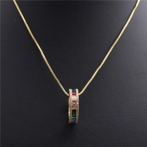 Macro shot of gold necklace featuring a circular pendant set with rainbow cubic zirconia