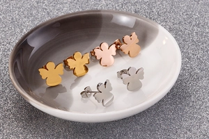 Three pairs of angel-shaped studs in gold, rose gold, and silver stainless steel finishes