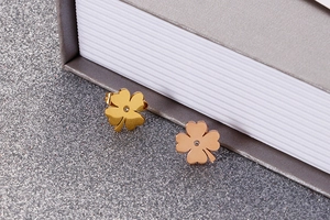 Macro shot of gold and rose gold clover stud earrings with center zircon stones