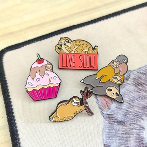 Set of four cute sloth enamel pins featuring LIVE SLOW slogan and colorful cartoon designs