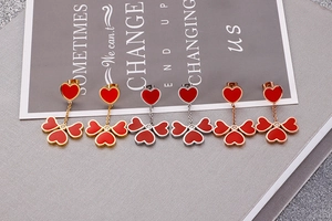 Detailed shot of heart-shaped clover tassel earrings in gold, silver, and rose gold