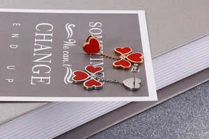 Detail view of red heart and clover earrings in rose gold and silver finishes