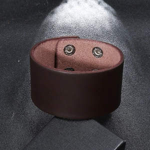 Detail view of dark brown leather cuff bracelet featuring four silver snap fasteners
