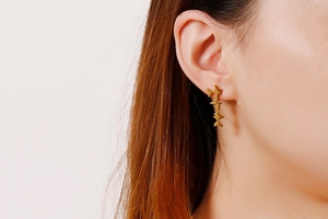Detail of gold fish heartbeat stud earring showing the vertical wave design on ear