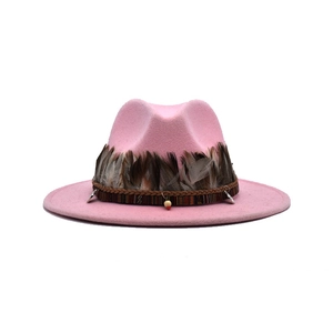 Detail of pink fedora featuring brown feathers, ethnic woven band and metallic pendant