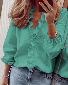 Dettaglio della camicetta verde acqua con scollo a V, volant e maniche a lanterna nel selfie