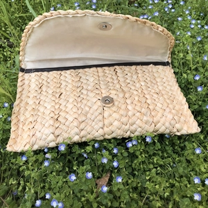 Dettaglio della pochette in paglia di mais con fodera interna liscia e chiusura a scatto in metallo
