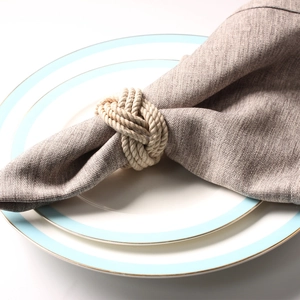 Handcrafted woven jute rope knot napkin ring on an elegant blue and gold rimmed plate