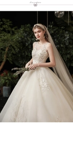 Detailed view of ivory wedding dress with 3D lace, sequins, and sheer illusion neckline