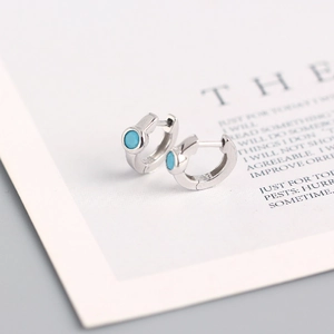 Macro detail of S925 sterling silver hoop earring with turquoise zircon inlay and 925 stamp