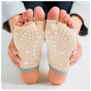 Close-up of beige toeless yoga socks with white silicone anti-slip dots on the soles
