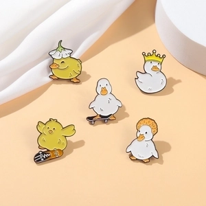 Set of 5 cute duck enamel pins with crown and skateboard motifs on beige background