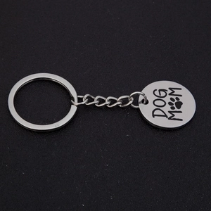 Polished stainless steel Dog Mom keychain with paw print pendant on black background