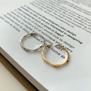 Close-up of minimalist gold and silver wavy irregular rings on a vintage book page