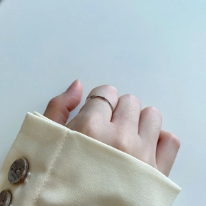 Detailed view of an irregular thin silver ring worn against a chic yellow blazer cuff