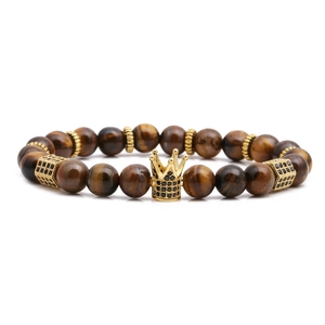 Macro detail of tiger eye stone beads with a gold crown charm inlaid with black zircons