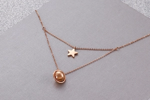 Detail of rose gold double-layered necklace with star and planet pendants and fine O-chains