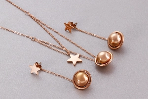 Detail of rose gold jewelry set with star and planet pendants on dual-layer necklace