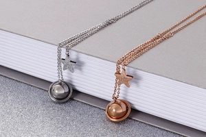 Detailed view of star and planet pendant necklaces in silver and rose gold finishes