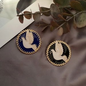 Close-up of vintage peace dove enamel brooches in blue and black with gold rope borders