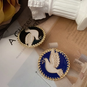 Close-up of enamel peace dove brooches with golden olive branches in blue and black