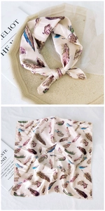 Detail of silk-like square scarf with elegant multi-color feather print on a tray