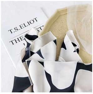 Close-up of black and white printed silk scarf on an open book for elegant display