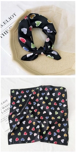 Close-up of black silk square scarf with colorful heart patterns on art tray
