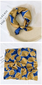 Detail of silk-feel square scarf with blue and gold abstract leaf print and satin finish