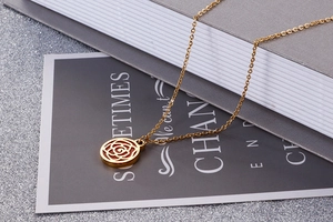 Detailed view of gold rose pendant necklace resting on a book with artistic typography