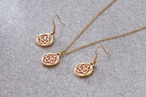 Detailed view of red rose floral pendants on gold titanium steel necklace and earrings set