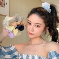 Close-up of colorful organza scrunchies in light blue, white, and purple on a ponytail