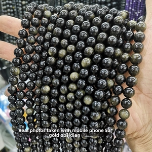 Macro shot of polished 5A gold obsidian beads showing distinct golden sheen and smooth texture