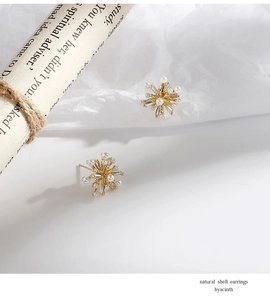 Detailed shot of gold flower stud earrings with sparkling zircon and white pearls