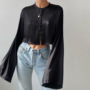 Gros plan détaillé d'un cardigan court en satin noir avec manches longues et boutons