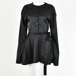 Détail d'un ensemble deux pièces en satin noir avec manches longues et lien taille