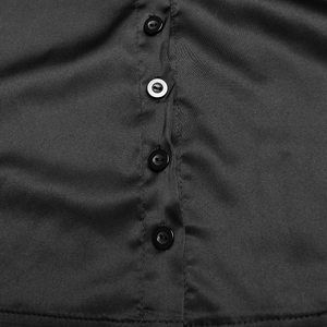 Détail du tissu en satin noir avec une rangée de quatre boutons et des coutures précises