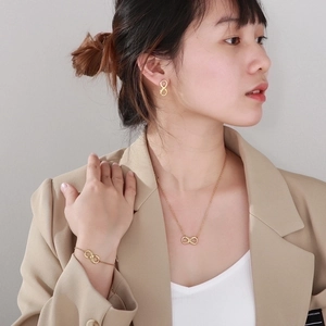 Elegant gold titanium steel jewelry set featuring infinity symbol necklace and earrings