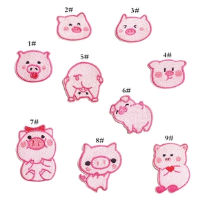 Macro detail of nine different cute pink pig cartoon embroidered patches with fine stitching