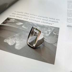 Macro shot of minimalist silver hollow rectangular ring on a lifestyle magazine background