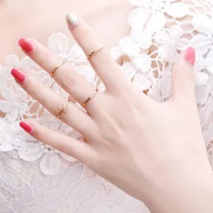 Primer plano de cinco anillos minimalistas de oro rosa usados por una modelo