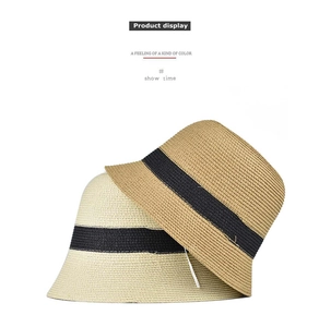 Detailed view of two woven bucket hats in beige and brown with black decorative bands