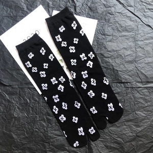 Detail shot of black Tabi socks featuring white cross patterns and ribbed cuffs